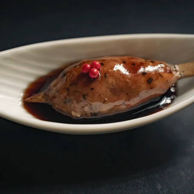 A tsukune (chicken meatball) skewer in a boat-shaped dish at Yakitori Suzune