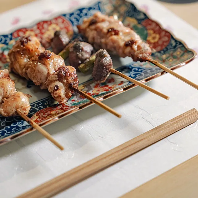 Skewers on a long plate at the counter of Yakitori Suzune
