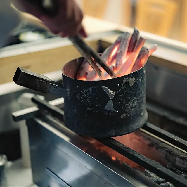 Adding charcoal to the grill at Yakitori Suzune
