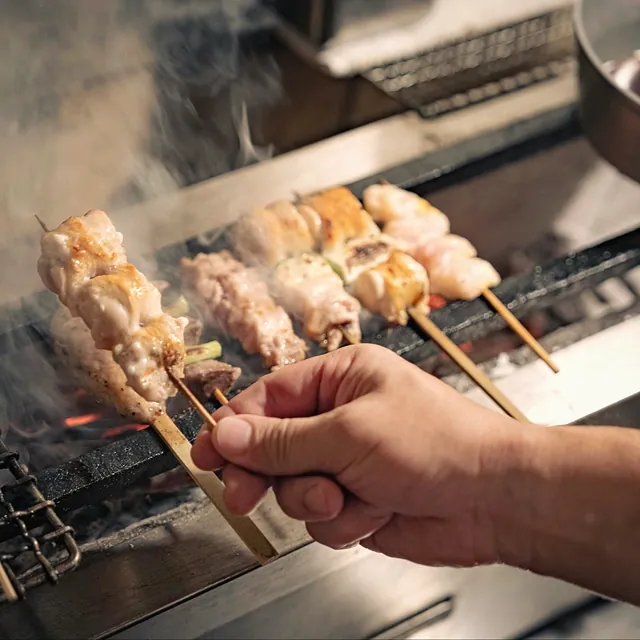 Taking a skewer off the grill at Yakitori Suzune