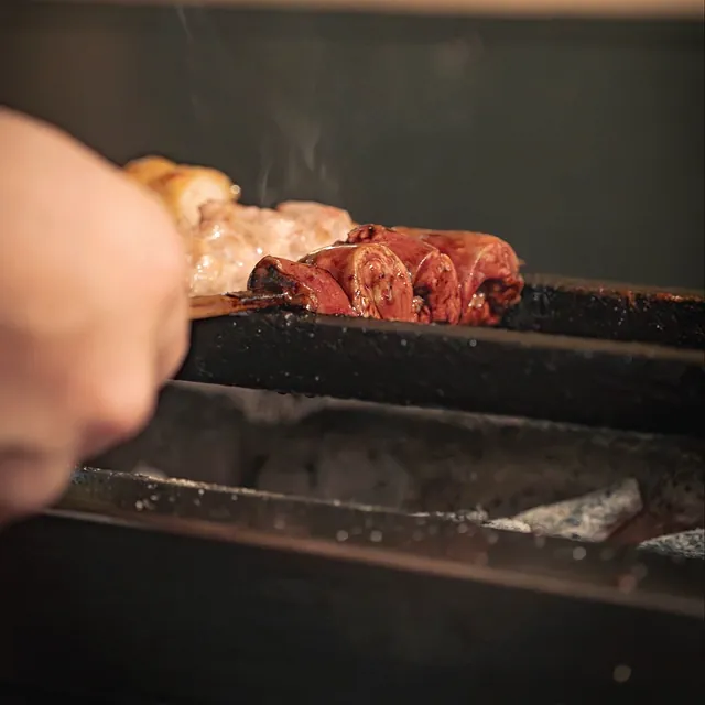 A skewer cooking on the grill at Yakitori Suzune