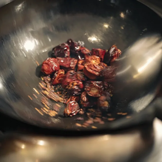 Stir-frying chili peppers in a wok at Yakitori Suzune