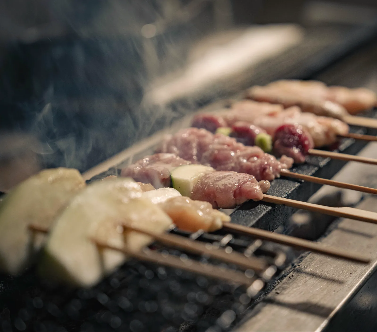 Yakitori Suzune의 연기가 피어오르는 그릴과 꼬치