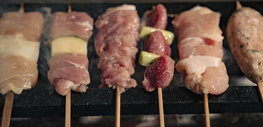 Yakitori Suzune의 그릴에 놓인 굽기 전 꼬치